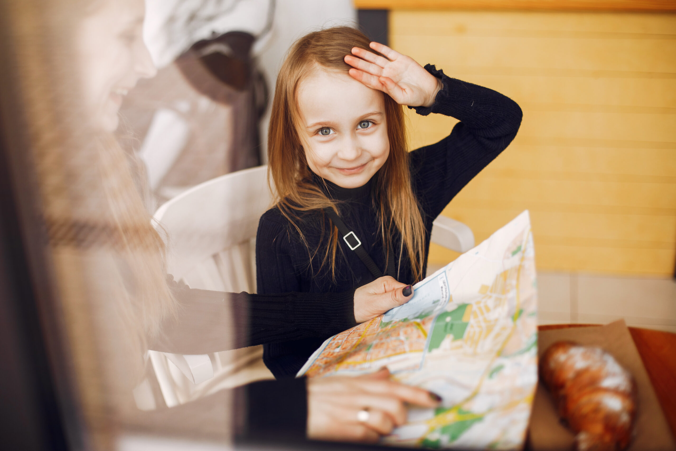 Fashionable mother with daughter. Family in a cafe. Girl with a croisant